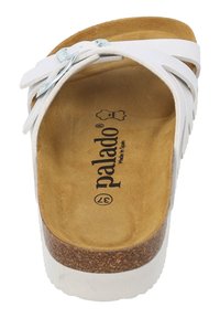 Vit halksandaler med korksål, mjuk brun innersula och silverfärgade spännen. Har flera remmar över ovansidan för stöd.