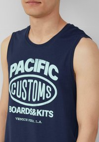 Granatowy bezrękawnik z bawełny, z jasnoniebieskimi grafikami: "PACIFIC CUSTOMS" nad "BOARDS & KITS" oraz "VENICE PIER, L.A."