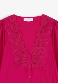 Blusa fucsia con scollatura a V e ricami floreali in pizzo. Presenta maniche a sbuffo e chiusura frontale con bottoni abbinati.