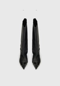 Fekete bőr, térdhosszúságú csizmák, amelyek szoros illeszkedésűek, hegyes orrúak és ezüst csat díszítéssel a nyílásoknál. Simább textúrájúak, látható minták nélkül.