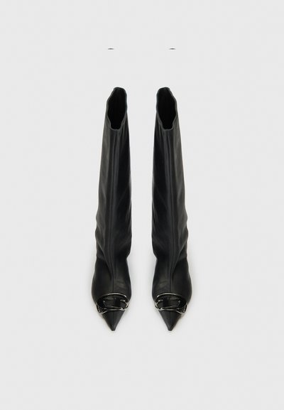 Bottes noires en cuir montant jusqu'au genou, ajustées, avec des bouts pointus et des accents de boucles en argent à l'ouverture. Texture lisse sans motifs visibles.