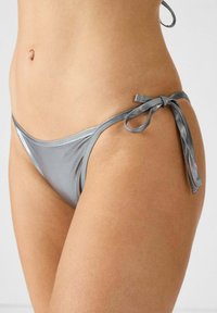 Silberner metallischer Bikini-Höschen mit glatter Textur, Krawatten-Seitendetail und minimaler Bedeckung, das ein elegantes Design und glänzende Oberfläche aufweist.