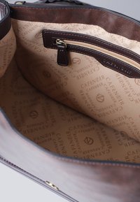 Interieur van een bruine leren handtas met een gladde stoffen voering met herhaaldelijke "CAFENOIR" branding. Bevat een ritsvak en gouden hardware.