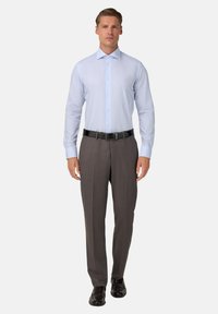 Lichtblauw, langetermijn overhemd met een subtiel ruitpatroon, gecombineerd met donkergrijze broek en een zwarte riem, gedragen met zwarte schoenen.