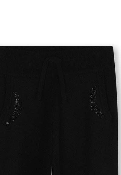 Zwarte joggers met een geribde tailleband en trekkoord. Voorzien van rhinestone accenten op de zakken. Zachte textuur en een relaxte pasvorm.