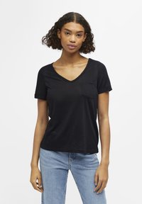 Zwarte korte mouw V-hals T-shirt met een borstzak, gemaakt van lichte stof, gecombineerd met lichtblauwe jeans. Eenvoudig, casual ontwerp.