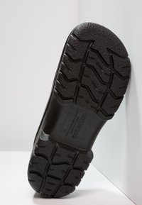 Schwarze Gummisohle mit einer strukturierten, gemusterten Oberfläche; verfügt über tiefe Profilierungen für Halt; geprägte Marken- und Größenangaben.