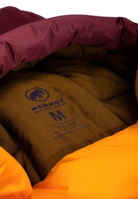 Interno di una giacca imbottita arancione e bordeaux, caratterizzato da un tessuto marrone testurizzato con un logo e un'etichetta delle taglie. Cuciture dettagliate visibili.