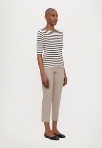 Haut en tricot rayé en crème et bleu marine, avec des manches trois-quarts ; associé à un pantalon cropped beige clair et des ballerines noires.