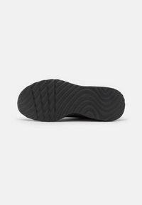 Black rubber shoe sole with a wavy texture and horizontal grooves for traction, featuring a rounded toe and flat profile.