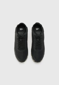 Black athletic sneakers with fabric upper, round toe, lace-up design, and textured rubber soles. Features white accents on heel and logo.