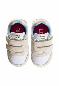 Sneakers grigio chiaro e bianchi con strap in Velcro, tessuto liscio e collare imbottito. Le suole interne riportano la scritta "LE RAGAZZE CORRONO PIÙ VELOCE."