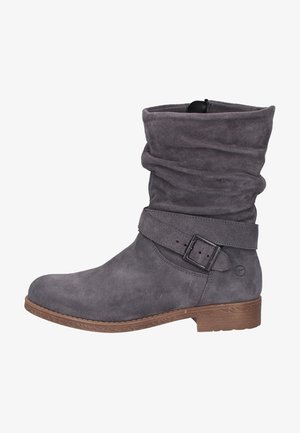 Stivaletto alla caviglia in suede grigio con design morbido, cinturino regolabile con fibbia, tacco basso marrone e suola in gomma texturizzata.