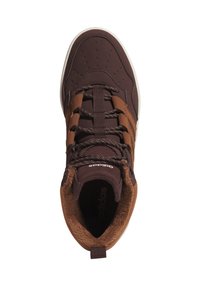 Braune Sportschuh mit strukturiertem Obermaterial, ausgestattet mit Schnürsenkeln und einer weichen, fellartigen Innenschicht. Enthält kontrastierende braune Akzente und eine weiße Sohle.