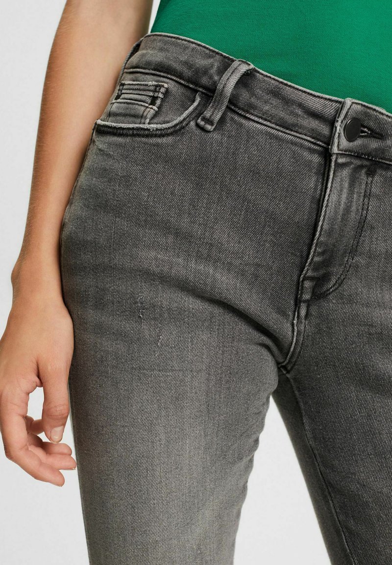 Graue Jeans aus Denim in Slim-Fit, mit einer Vordertasche, Gürtelschlaufen und einem Knopfverschluss. Der Stoff weist eine leichte Dehnbarkeit auf.