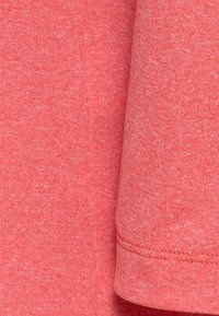 Campione di tessuto corallo con un motivo texturizzato e mélange. Cuciture visibili lungo il bordo; materiale morbido e elastico adatto per abbigliamento casual.