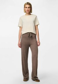 T-shirt en coton beige clair associé à un pantalon à cordon de serrage marron à côtes. Coupe décontractée avec une texture douce et des jambes droites.