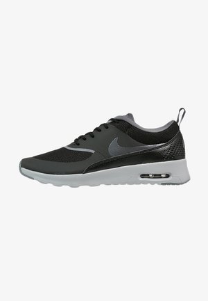 Black athletic shoe with a mesh upper, grey accents, textured heel, and visible air cushioning. Features a rounded toe and flexible sole.