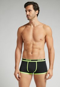 Černé boxerky s neonově zelenými detaily; elastický pás s logem, přiléhavý střih, hladká textura a kontrastní lemování.