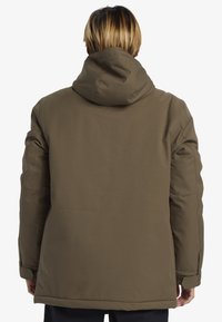 Brun vadderad jacka med huva, som har rak passform, elastiska ärmslut och sömnadsdetaljer på axlarna och sidorna.
