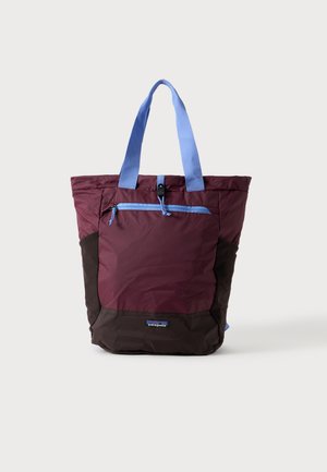 Zweifarbige, weiche Stofftasche in Burgunderrot und Dunkelbraun mit hellblauen Griffen und einer vorderen Reißverschlusstasche.
