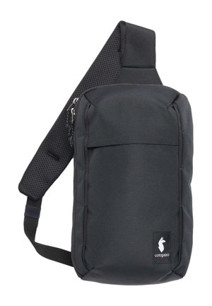 Bolso bandolera negro fabricado con tela resistente, con una correa acolchada y transpirable, compartimentos con cremallera y una etiqueta con el logo en el frente.
