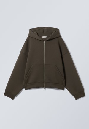 Sudadera con cremallera de color verde oscuro, con capucha, dos bolsillos frontales y mangas anchas. Fabricada en un tejido suave y texturizado con un ajuste relajado.
