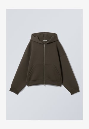 Sudadera con cremallera de color verde oscuro, con capucha, dos bolsillos frontales y mangas anchas. Fabricada en un tejido suave y texturizado con un ajuste relajado.