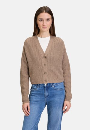 Cardigan marron à côtes avec un col en V, des boutons à l'avant et des manches longues, porté sur un haut blanc et associé à un jean bleu.
