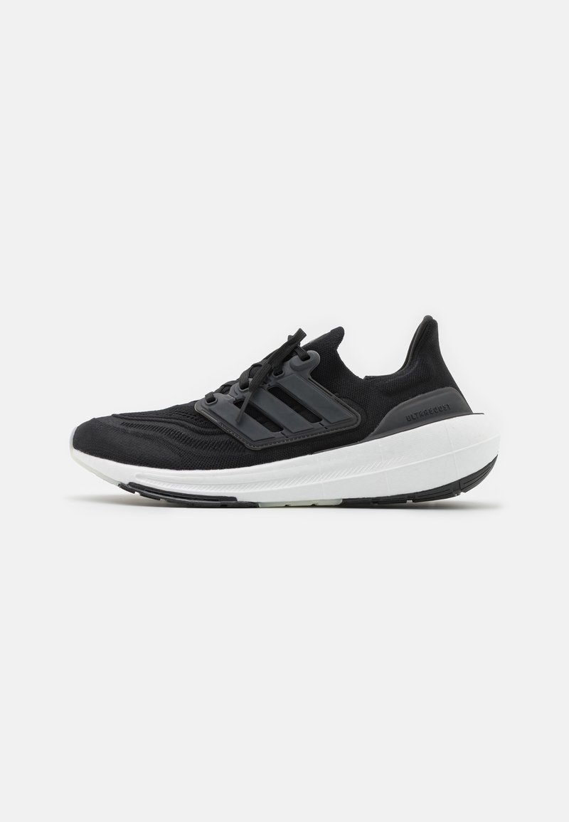 Scarpa sportiva nera con tomaia in maglia, design a tre strisce, lacci e suola intermedia bianca. Presenta dettagli testurizzati e un collo imbottito.