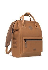 Zaino beige con design strutturato, dotato di una tasca anteriore con zip, manici superiori, spallacci regolabili e tessuto texturizzato. Dettaglio del logo rotondo.