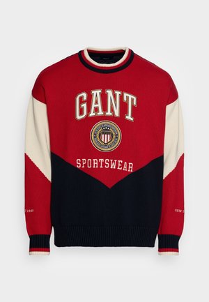 Rode, marineblauwe en crèmekleurige gebreide trui met "GANT" en "SPORTSWEAR" geborduurd. Voorzien van een geribde halslijn en manchetten, en een chevronpatroon.