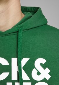 Felpa verde in cotone con cordino, decorata con grande testo bianco. Tessuto morbido con vestibilità rilassata e cappuccio ampio.