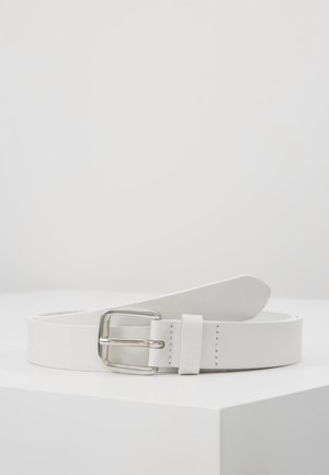 Ceinture en cuir blanc avec boucle rectangulaire argentée, posée à plat sur une surface blanche avec un fond gris clair uni.