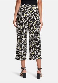 Culotte-broeken in een lichte stof met een abstract patroon in zwart, wit en olijfgroen; voorzien van een elastische tailleband en een cropped lengte.