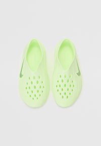 Scarpe slip-on verde lime con una superficie testurizzata e numerosi fori di ventilazione, caratterizzate da un piccolo logo Nike verde sul lato.