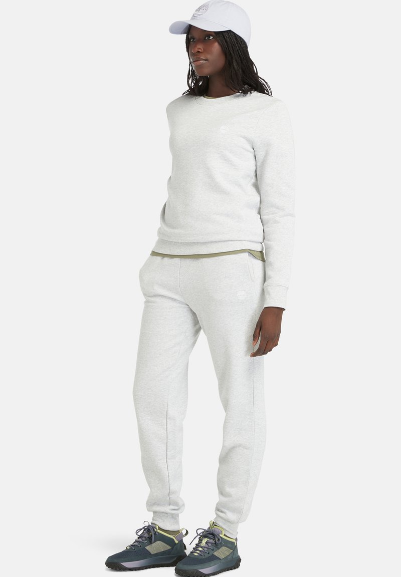 Felpa grigia chiara e pantaloni jogger abbinati, realizzati in tessuto morbido, abbinati a un cappellino azzurro chiaro e scarpe da ginnastica scure.