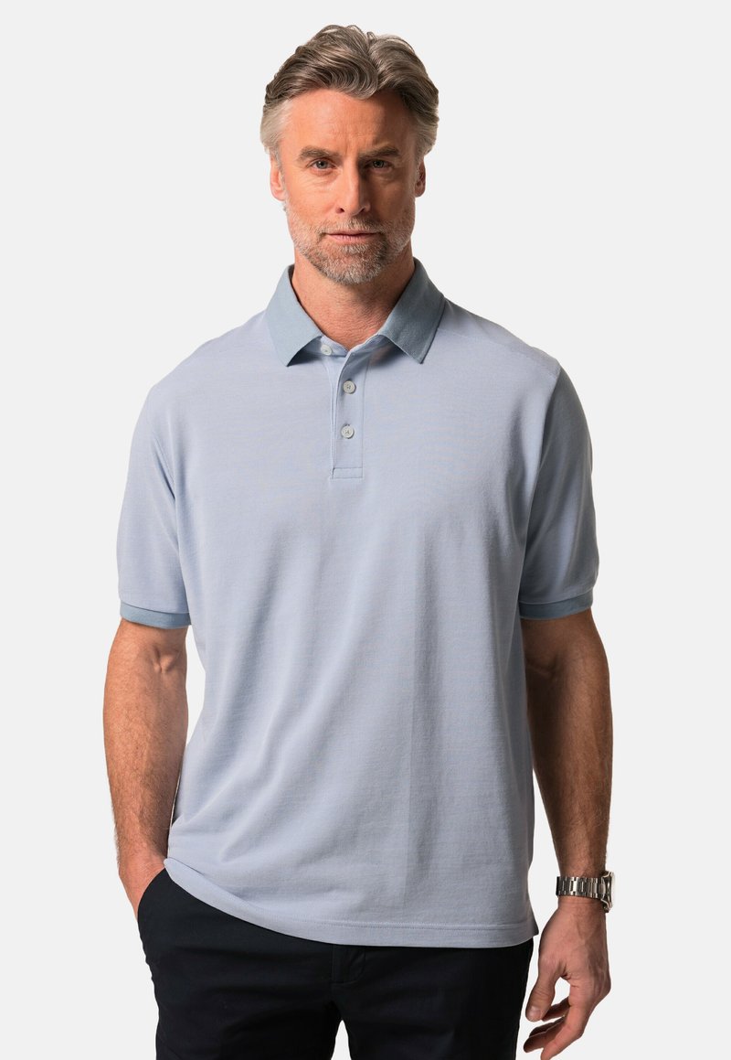 Jasnoniebieska koszulka polo z kontrastowym kołnierzykiem, krótkimi rękawami, trzema guzikami i teksturowanym materiałem. Uzupełniona zegarkiem na nadgarstku.