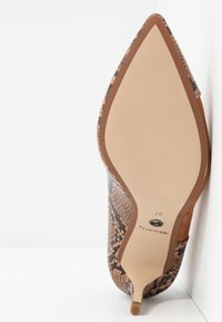Chaussure à talon haut à bout pointu avec motif peau de serpent et semelle beige, taille 37, posée sur une surface blanche sur fond blanc.