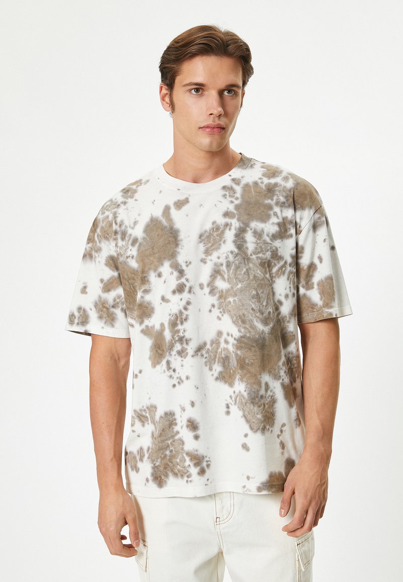 Kortærmet tie-dye t-shirt i hvid og brun. Har en afslappet pasform med rund halsudskæring og et blødt, tekstureret bomuldsstof.