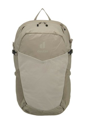Light beige backpack with front mesh pocket, top zipper closure, side compression straps, and a carry handle loop at the top.