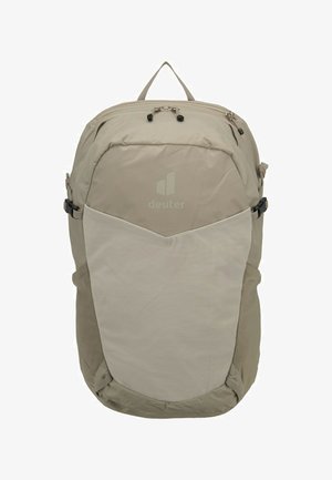 Light beige backpack with front mesh pocket, top zipper closure, side compression straps, and a carry handle loop at the top.
