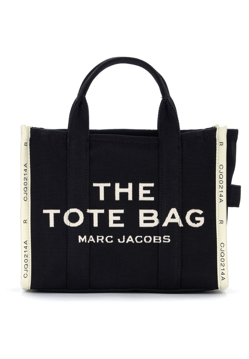 Mustmust kott musta kangaga kahelte käepidemetega. Omab valget teksti "THE TOTE BAG" ja "MARC JACOBS." Lukuga ülemine osa ja külglabeli aktsendid.