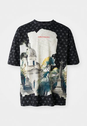 T-shirt noir à manches courtes avec un imprimé architectural coloré sur fond de verdure, superposé à un tissu à motifs. Le texte "CARLO COLUCCI" figure sur le devant.