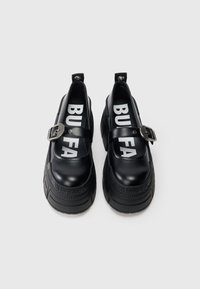 Sorte platåsko med glatt skinnfinish. Har en spenne-strap og fet "BUFFALO"-logo på innersålen. Tykk såle av gummi.