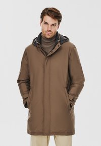 Brązowy ocieplany płaszcz z kapturem, z gładką powierzchnią, z przodu na zamek i bocznymi kieszeniami. Noszony na szary golf.