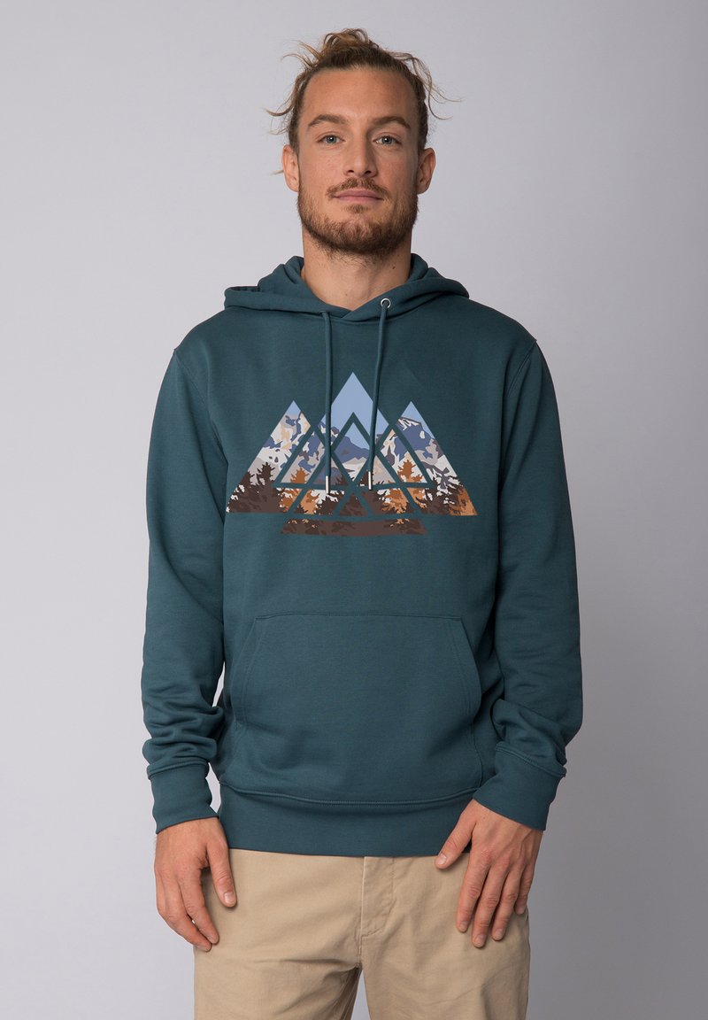 Sweat à capuche teal avec un motif de montagne dans des teintes de bleu, marron et crème. Il possède une poche avant et des cordons de serrage à la capuche.
