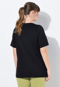 T-shirt nera a maniche corte con vestibilità rilassata, realizzata in materiale morbido. Presenta un collo tondo e un orlo dritto.