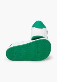 Zapato infantil verde y blanco con suela de goma texturizada, puntera redonda y correas de velcro. Presenta acentos grises y una marca grabada en la suela.