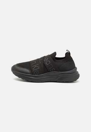 Sneaker sportive nere con tomaia in rete, doppiose cinghie regolabili, suola testurizzata e pull tab sul tallone per indossarle facilmente.